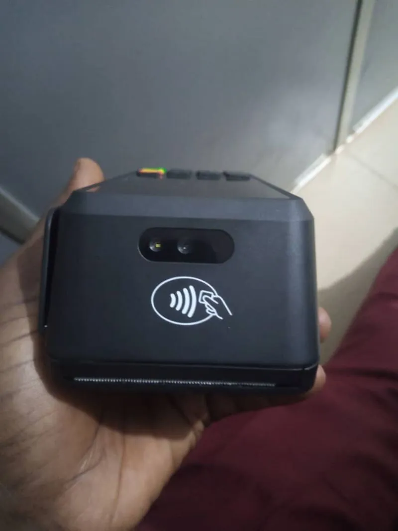 The back of the POS terminal held in a hand, showing the camera lens above the contactless payment symbol.